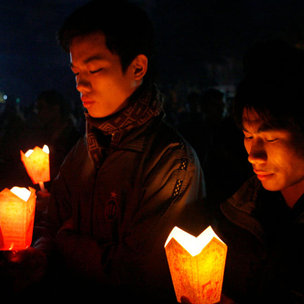 two men praying or meditating with candles